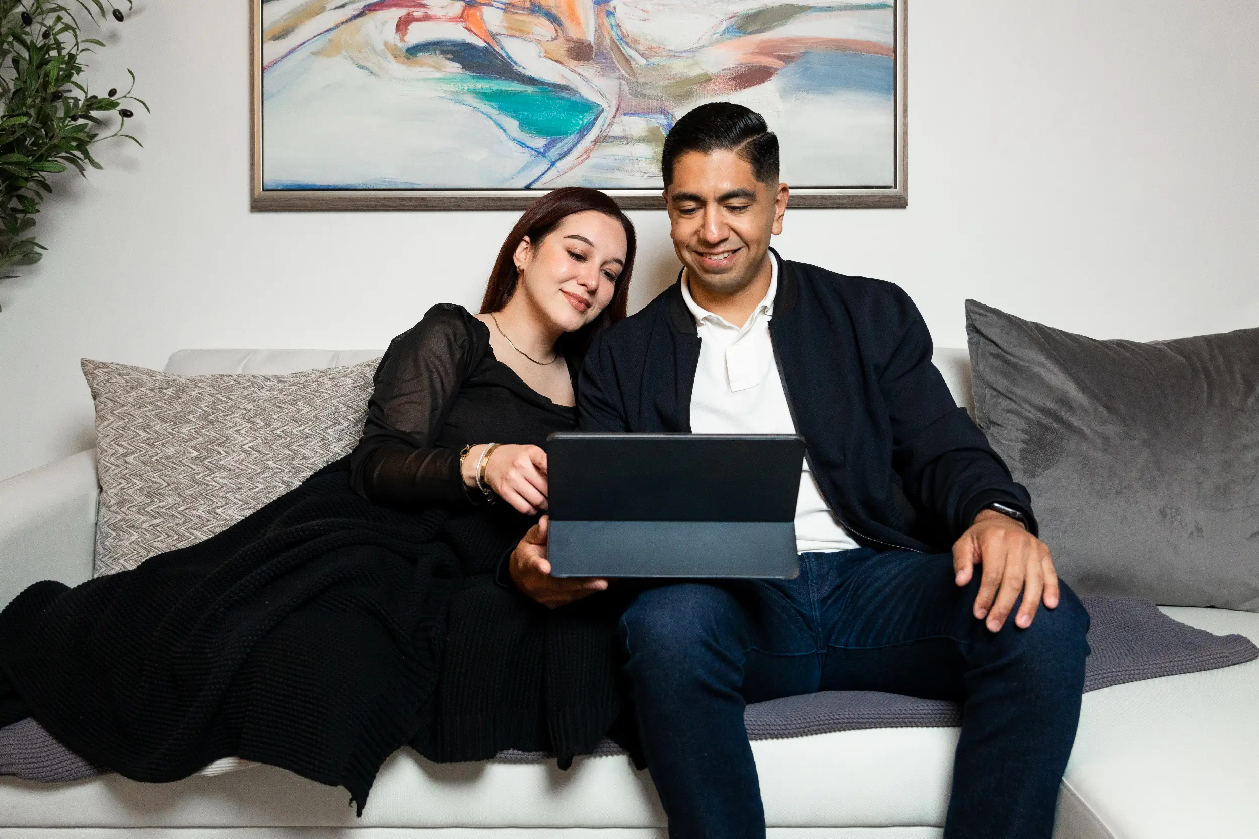 Pareja viendo videos en un ipad en la sala de su nueva casa.