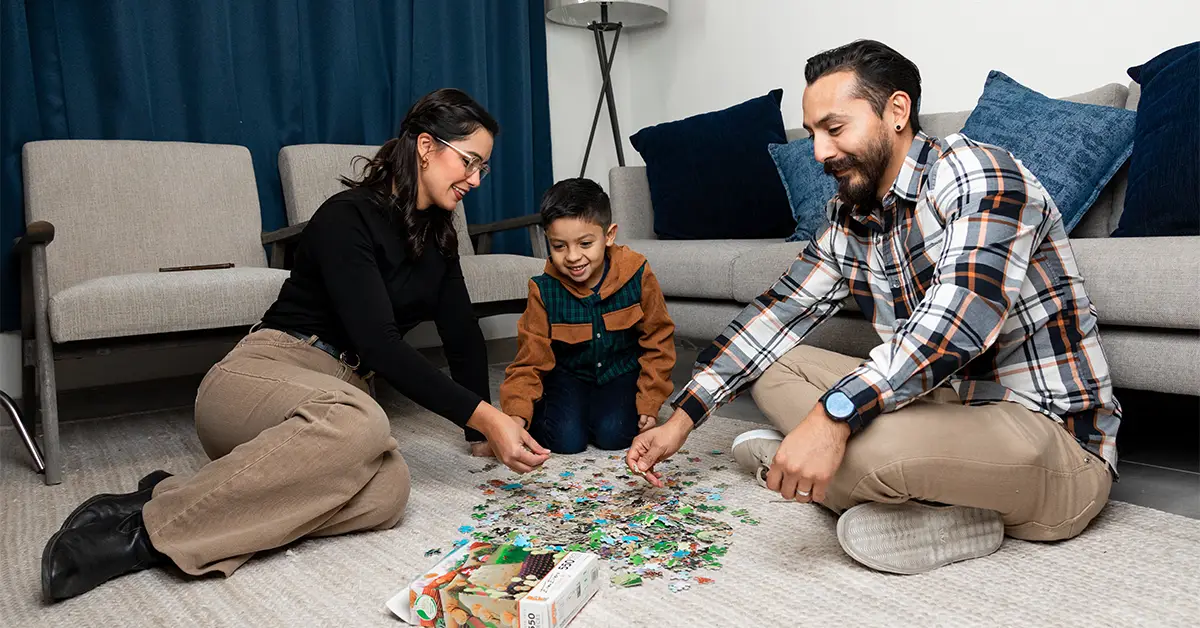 Familia armando un rompecabezas en la sala de su casa.
