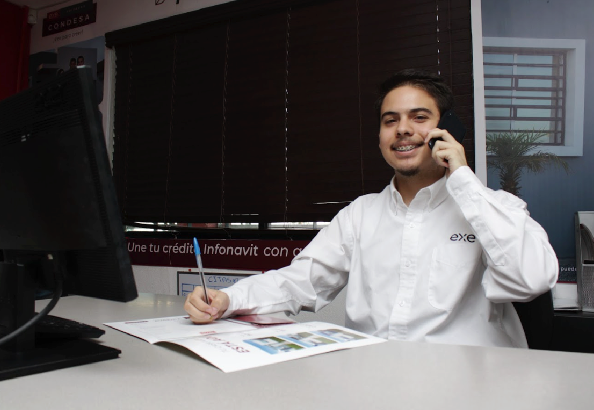 Hombre sentado en un escritorio hablando por teléfono móvil acerca del buró de crédito.