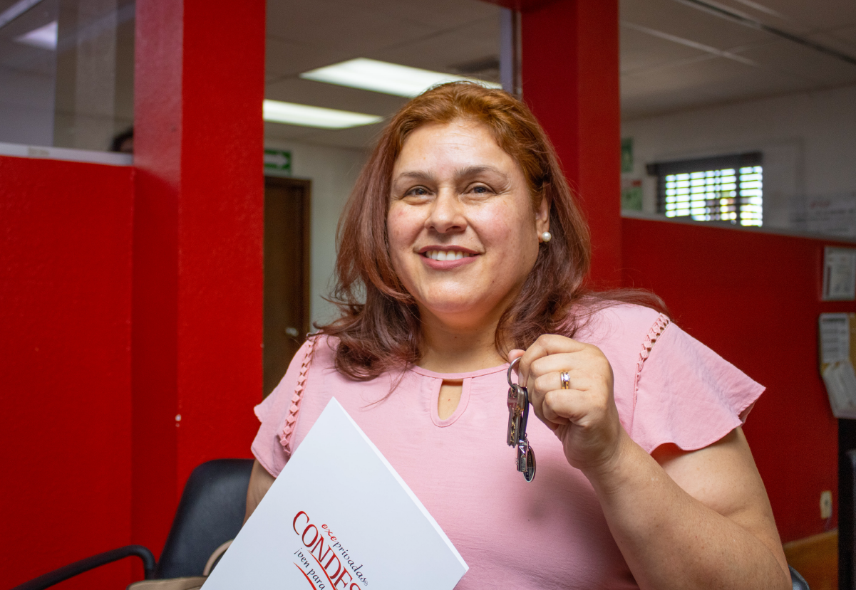 Mujer sonriente recibiendo las llaves de su nueva casa que compro con el buró de crédito.