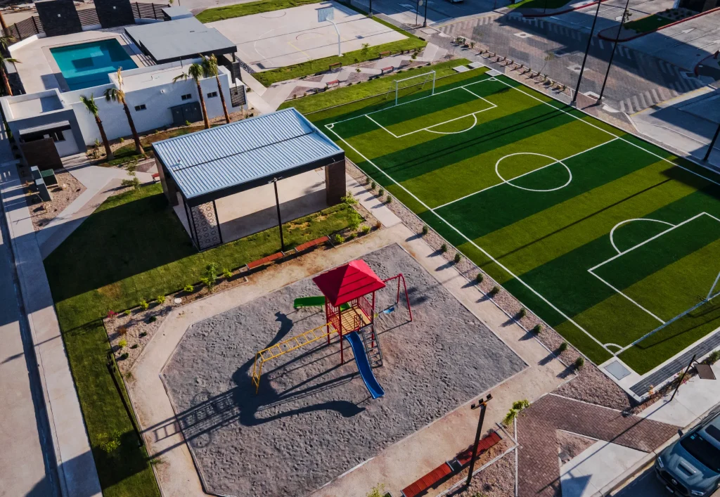 Vista area de residencial con cancha de futbol 7, juegos y picina