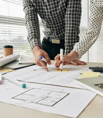 Dos personas haciendo unos planos en una mesa.